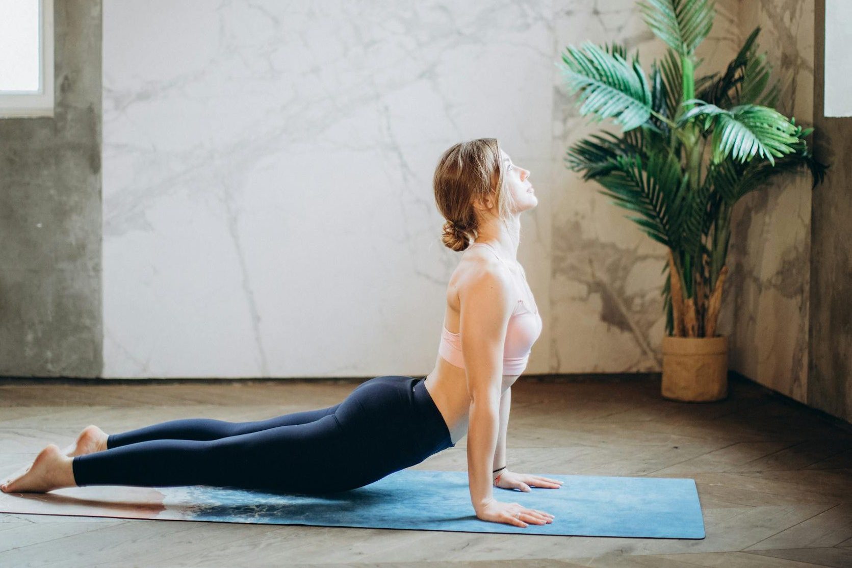mulher com roupas confortáveis fazendo uma postura de yoga no chão.